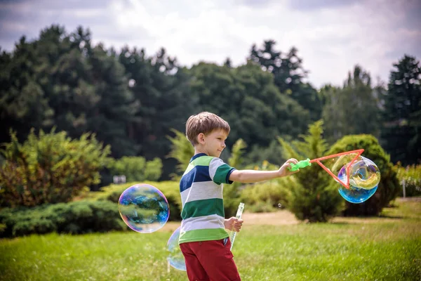 Little boy playing with his soap bubbles toy in the park. Child activity. Springtime concept — Stock Photo, Image