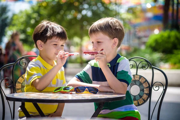 Dos niños pequeños que esperan en la mesa para desayunar sano en el restaurante del hotel o en la cafetería de la ciudad. Niño sentarse en silla cómoda jugar con aviones de juguete, relajado, disfrutar de sus vacaciones. Vacaciones de verano con c —  Fotos de Stock