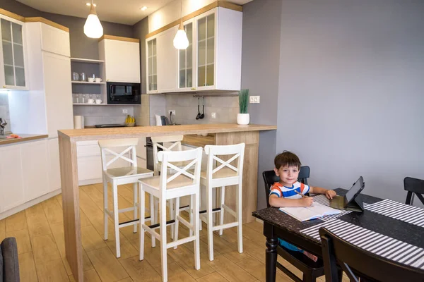 Préado intelligent écolier faire ses devoirs avec tablette numérique à la maison. Enfant utilisant des gadgets sur sa cuisine pour étudier. Éducation et apprentissage modernes pour les enfants — Photo