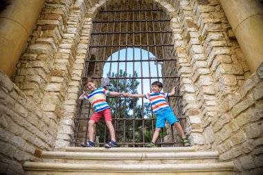 Genç kardeşler antik bir taş kapının yanında. Çocuklar gülümsüyor ve mutlu bir yaz tatili geçiriyorlar.