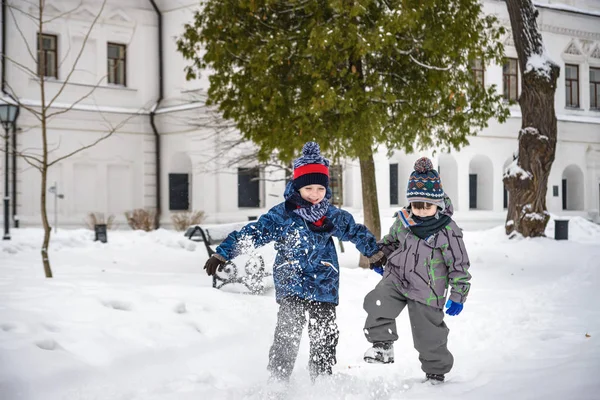 İki küçük çocuk renkli giysiler içinde, kar yağarken açık havada. — Stok fotoğraf