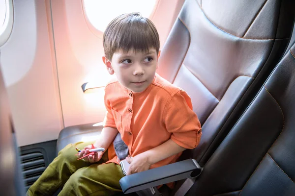 Child in airplane. Kid in air plane sitting in window seat. Flig