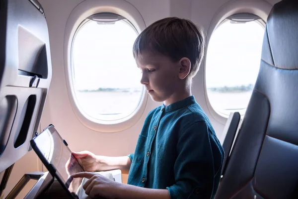 Милий шестирічний хлопчик, граючи на таблоїді в літаку на кабані, т — стокове фото