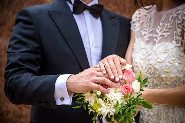 Pastellfarbener Brautstrauß in Nahaufnahme vor den Augen des Brautpaares - Bräutigam und Braut mit eleganter Maniküre. Blumen lagen auf dem Kleid mit Schwanenfeder-Dekor — Stockfoto