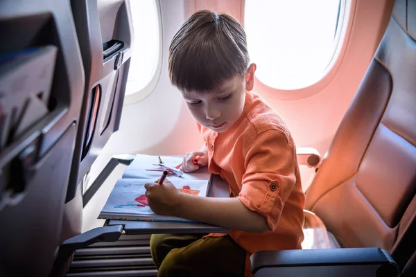 Чарівна дитина подорожує літаком. Радісний маленький хлопчик сидить — стокове фото