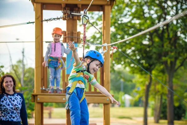Uroczy chłopiec cieszący się czasem spędzonym w linowym placu zabaw w parku przygód, — Zdjęcie stockowe