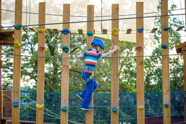 Chłopiec zabawy w parku przygód. maluch wspinaczka w liny PLA — Zdjęcie stockowe