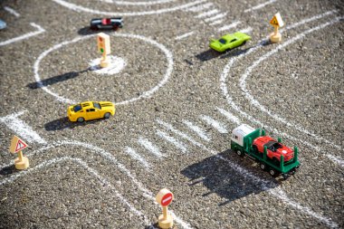 Oyuncak arabalar yolda siyah asfalta tebeşirlenmiş kırmızı yeşil mavi renk. Zorlu trafik kuralları kavramı.