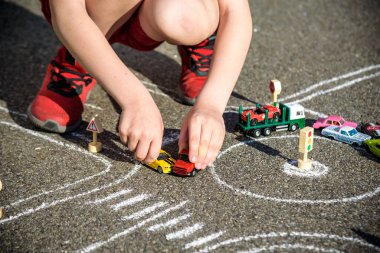 Komik çocuk tebeşirle trafik arabası çizerken eğleniyor. Yazın açık havada çocuklar için yaratıcı bir eğlence. Trafik kuralları konsepti zordur. Kapat.