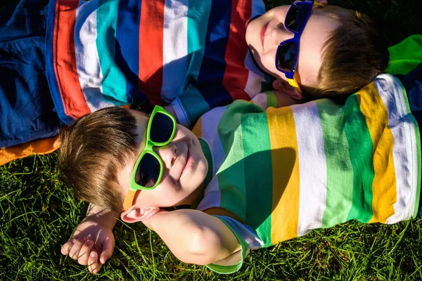 Felices Niños Sonrientes Alegres Tendidos Una Hierba Con Gafas Sol — Foto de Stock