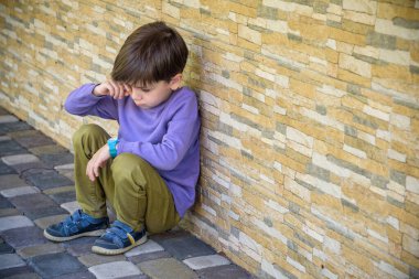 Okulda yalnız oturan üzgün çocuk yüzünü gizliyor. İzolasyon ve zorbalık kavramı. Çocuk üzgün ve mutsuzdu, çocuk ağlıyordu, üzgündü, hastaydı..