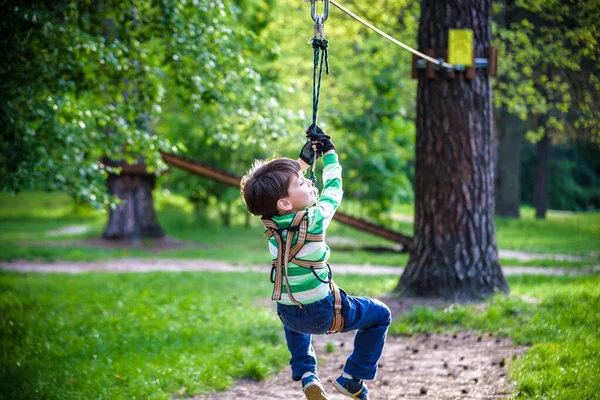 smiling boy rides a zip line. happy child on the zip line. The kid passes the rope obstacle course.