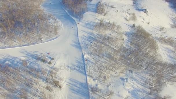 Skidåkare och snowboardåkare glida ner bergssidan nära sjön Bannoe. Antenn — Stockvideo