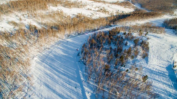 Sciatori e snowboarder scivolano lungo la montagna vicino al lago di Bannoe. Aerea — Foto Stock