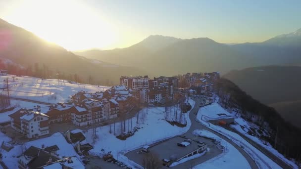 Coucher de soleil dans les montagnes enneigées et les bâtiments. Aérienne, Rosa Khutor — Video