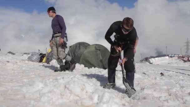 2014 07 Ελμπρούς, Ρωσία: ένας άνθρωπος είναι το σκάψιμο χιόνι για να εγκαταστήσετε μια σκηνή — Αρχείο Βίντεο