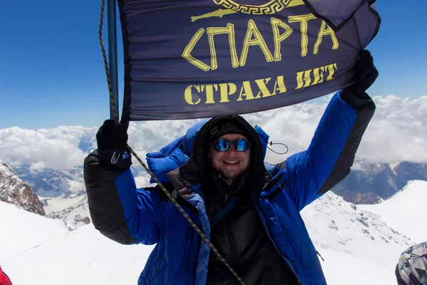 2014 07 Ελμπρούς, Ρωσία: άνθρωπος που κρατά την σημαία της Σπάρτης στην κορυφή του Ελμπρούς — Φωτογραφία Αρχείου