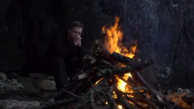 bir sakallı bir adam yangın mağarada yakınındaki bakar