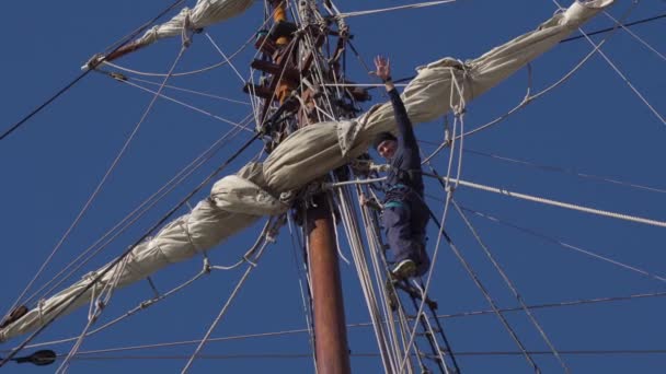 Le marin descend le mât en hauteur sur un voilier et sourit . — Video