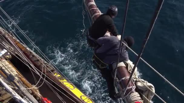 Segler arbeiten mit Segeln in luftiger Höhe auf einem traditionellen Segelboot — Stockvideo