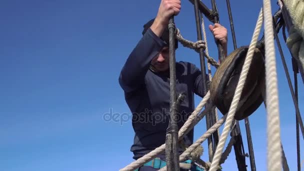 Denizci bir yükseklikte direk aşağı bir yelkenli gülümsüyor devam ediyor. — Stok video