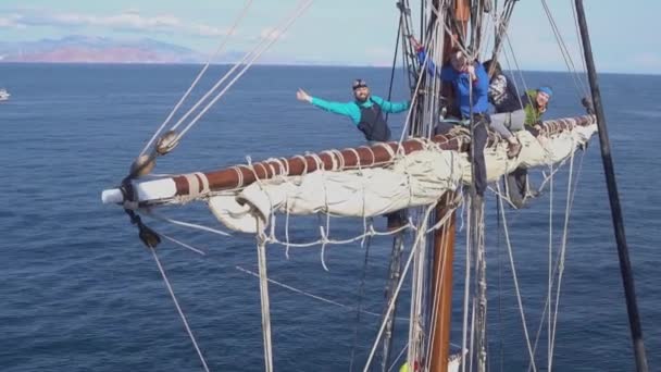 Segler arbeiten mit Segeln in luftiger Höhe auf einem traditionellen Segelboot — Stockvideo