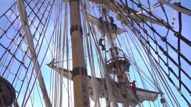 Моряки поднимаются на мачту по веревочной лестнице на традиционном парусном судне . — стоковое видео