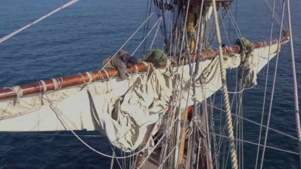 Моряки работают с парусами на высоте на традиционном паруснике — стоковое видео
