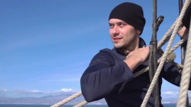 Bir denizci bir yelkenli üzerinde bir yükseklikte bir direk üzerinde asılı ve mesafe içine görünüyor