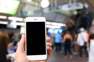 Metro istasyonunun arka planında akıllı telefon var.