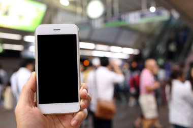 Metro istasyonunun arka planında akıllı telefon var.