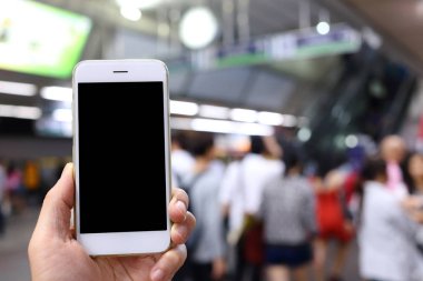 Metro istasyonunun arka planında akıllı telefon var.