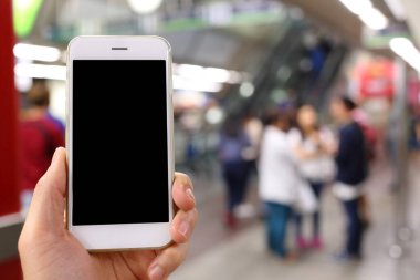 Metro istasyonunun arka planında akıllı telefon var.