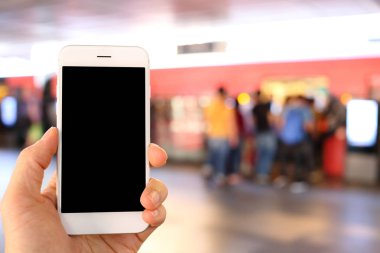 Metro istasyonunun arka planında akıllı telefon var.