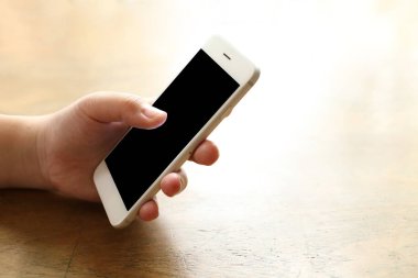 Masanın üzerinde akıllı telefon tutan kadın.