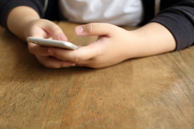 Masanın üzerinde akıllı telefon tutan kadın.