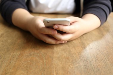 Masanın üzerinde akıllı telefon tutan kadın.