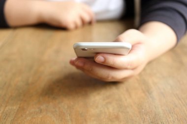 Masanın üzerinde akıllı telefon tutan kadın.