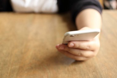 Masanın üzerinde akıllı telefon tutan kadın.