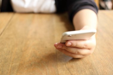 Masanın üzerinde akıllı telefon tutan kadın.