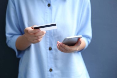 Kredi kartı ödeyen bir kadın akıllı telefondan online alışveriş yapıyor.