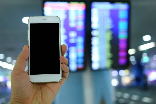 Hand holding smartphone with flight board backgroun