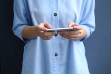 Akıllı telefon kullanan mavi gömlekli bir kadın.