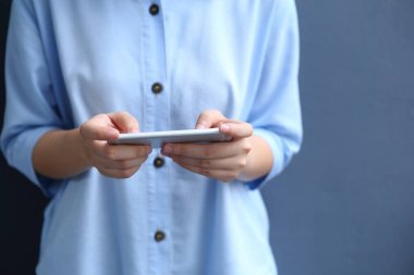 Akıllı telefon kullanan mavi gömlekli bir kadın.