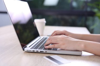 Ecommerce concept, Woman using ecommerce website via laptop with credit cart on wooden desk