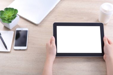 Hand holding tablet with smartphone and laptop on wooden desk, Tablet mockup for webdesign and user interface