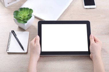 Hand holding tablet with smartphone and laptop on wooden desk, Tablet mockup for webdesign and user interface