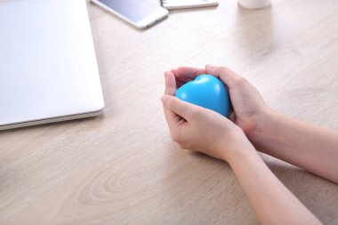 Hand holding ball heart shape on wooden desk