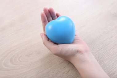 Hand holding ball heart shape on wooden desk
