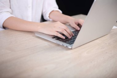 Ahşap masanın üzerinde dizüstü bilgisayar kullanan iş kadın